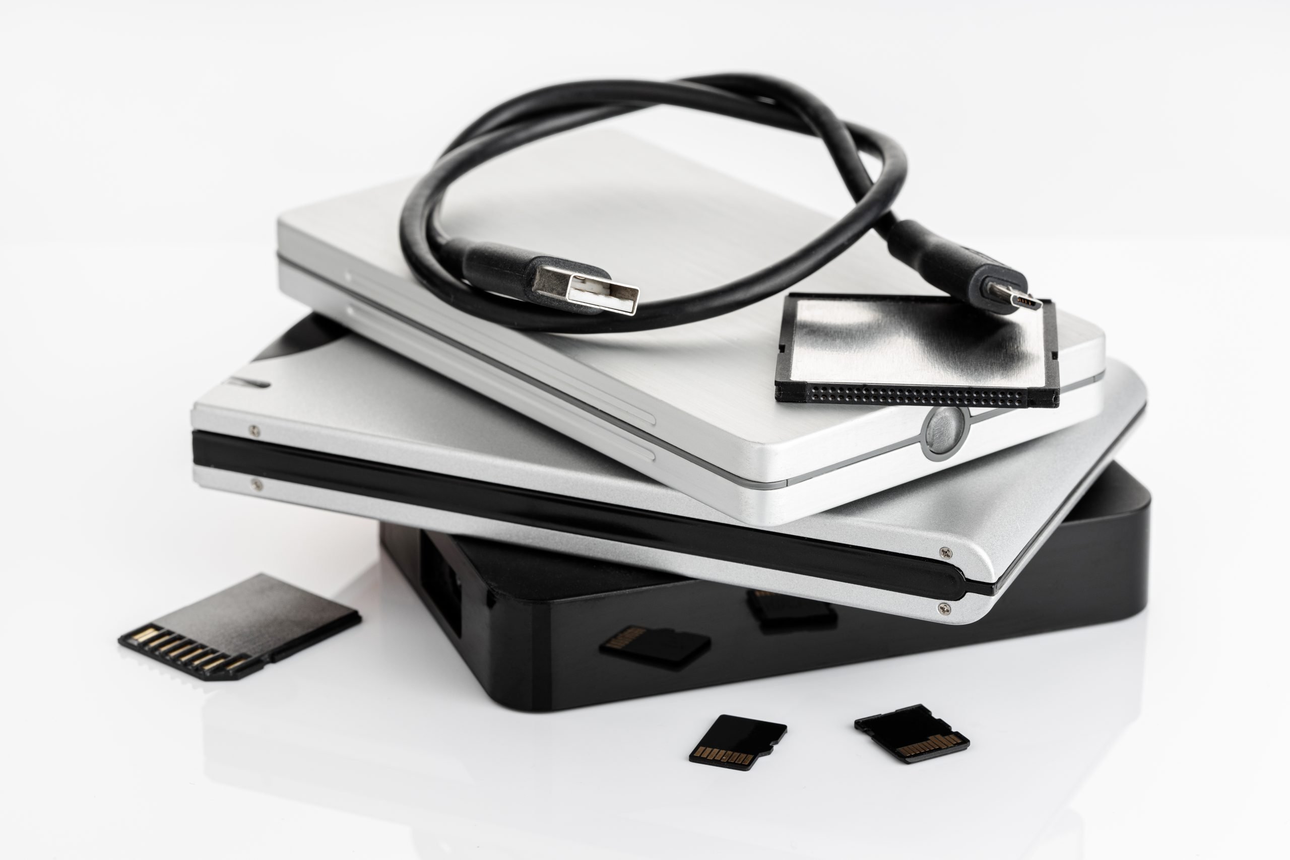 Group of external Hard disks and memory cards on white table. Data storage concept